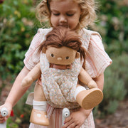 A beige floral-patterned Olli Ella Doll Carrier with padded straps designed for carrying dolls.