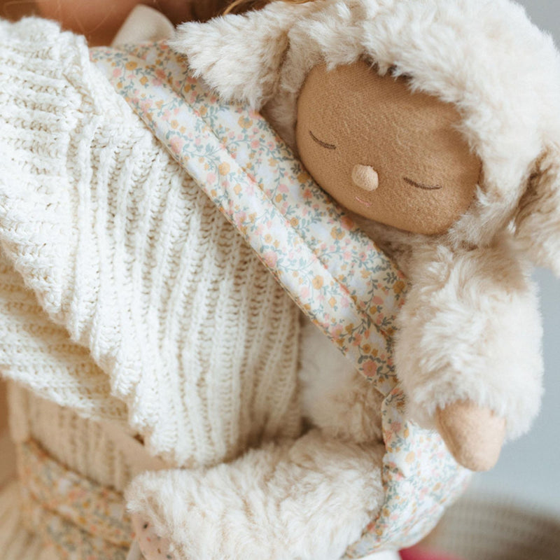 A beige floral-patterned Olli Ella Doll Carrier with padded straps designed for carrying dolls.