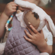 A qulited lavender Olli Ella Doll Carrier with padded straps designed for carrying dolls.